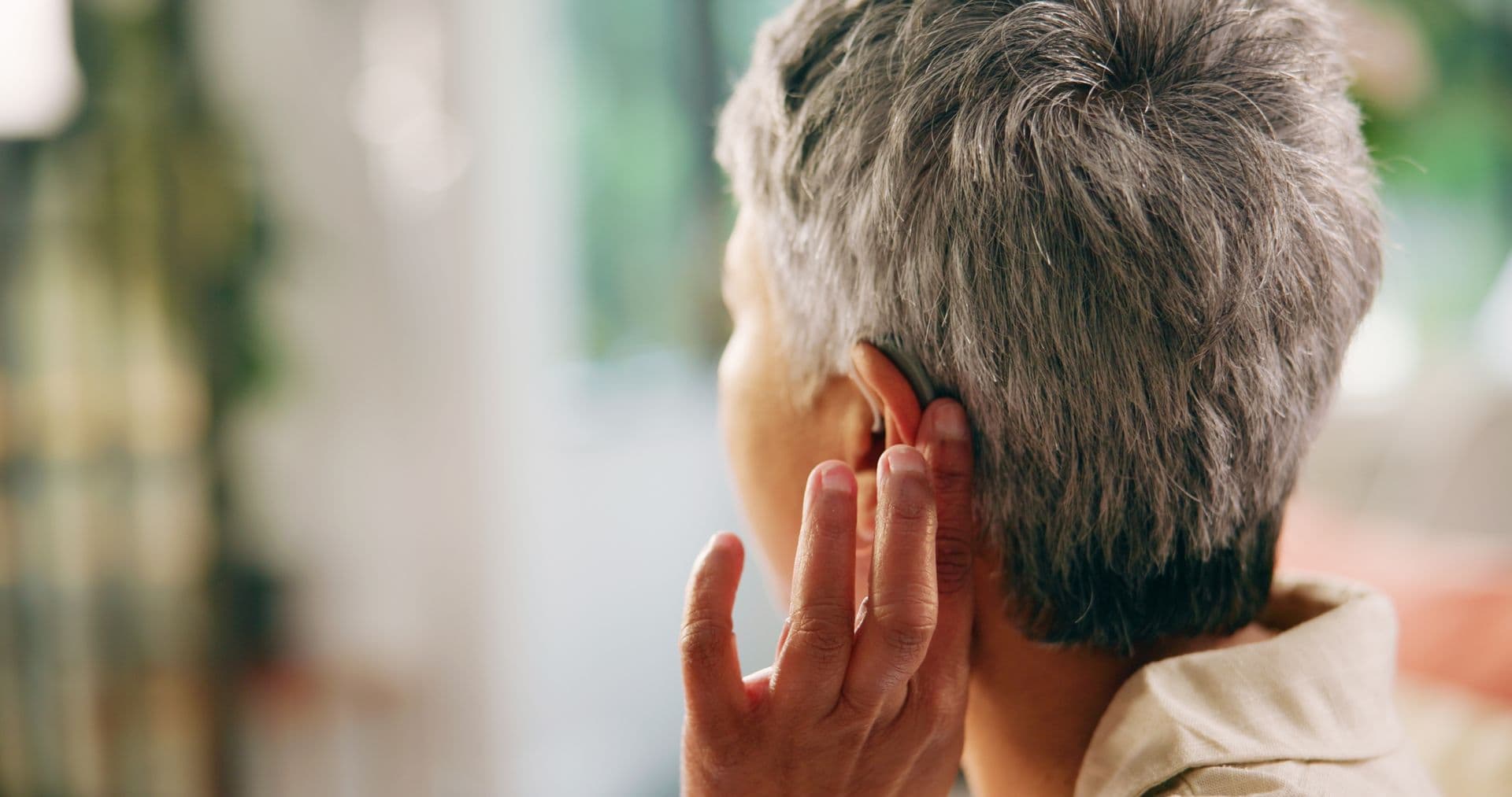 A woman gently touching her hearing aid